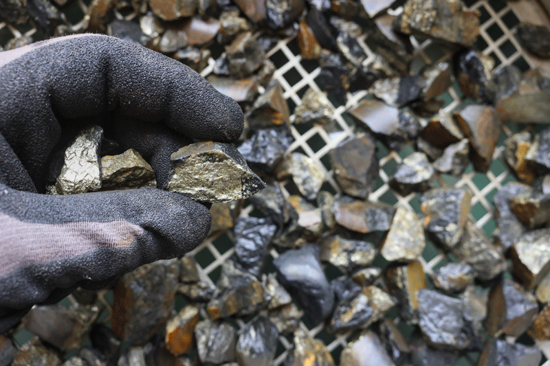 A metal stone being held by someone wearing gloves