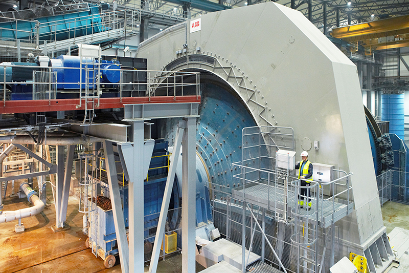 giant metal rotating flywheel in a warehouse with an engineer in a safety gear dwarfed by it