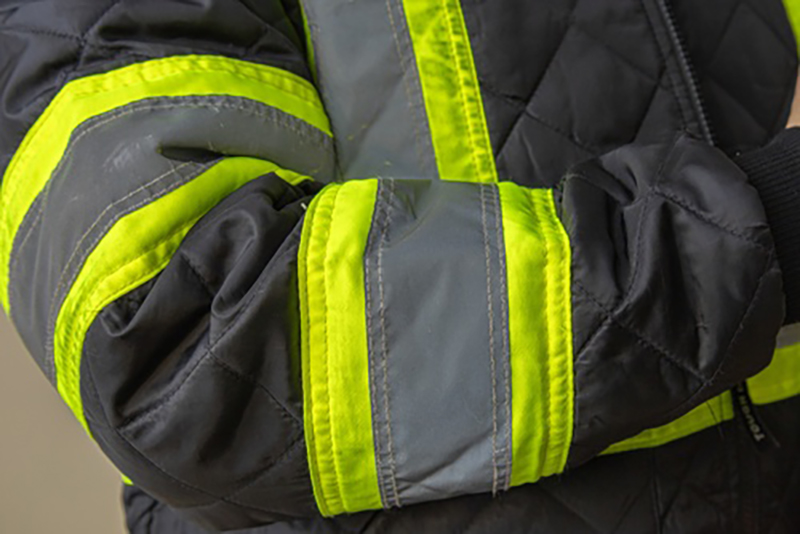The sleeve of a workers jacket with high-vis reflective stripes
