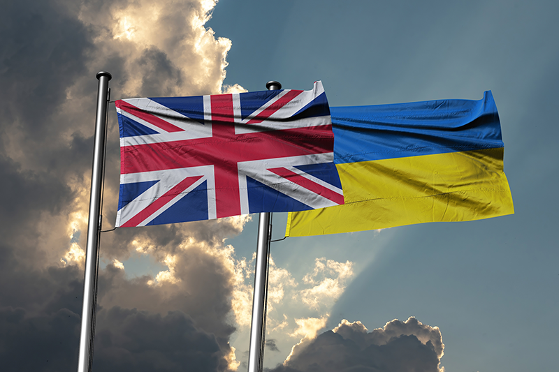Stock image of UK and Ukraine flags next to each other against the sky