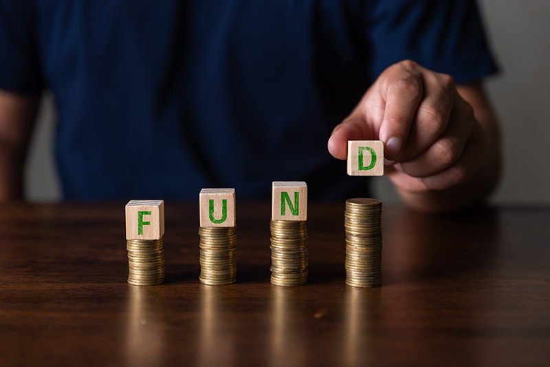 Four stacks of coins with blocks spelling out 'FUND' on top of them