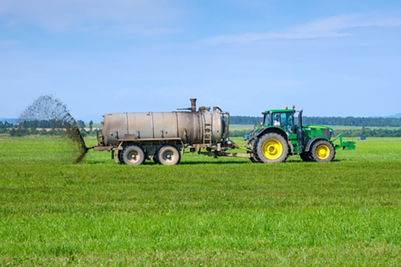 A tractor spreading fertiliser on a field