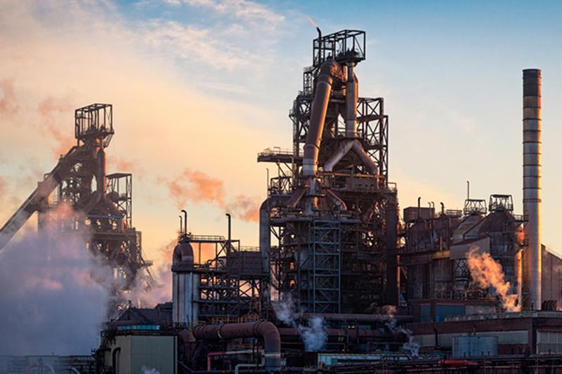 Industrial factory with lots of external pipes and chimneys and some water vapour/smoke