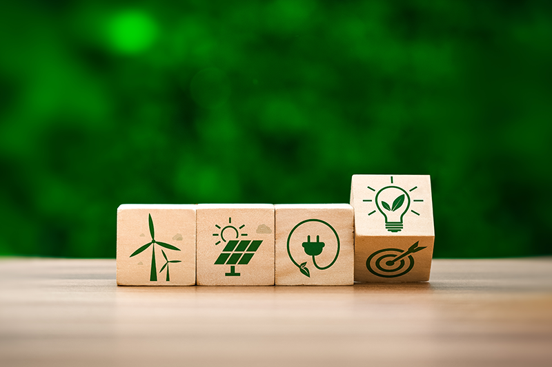 Stock image of four wooden blocks in a row showing green-coloured icons related to renewable energy goals