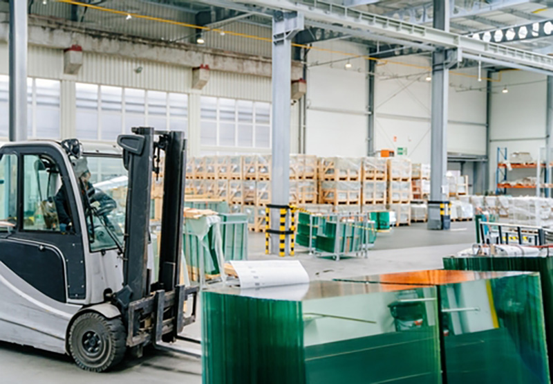 Forklift moving glass panes in a warehouse