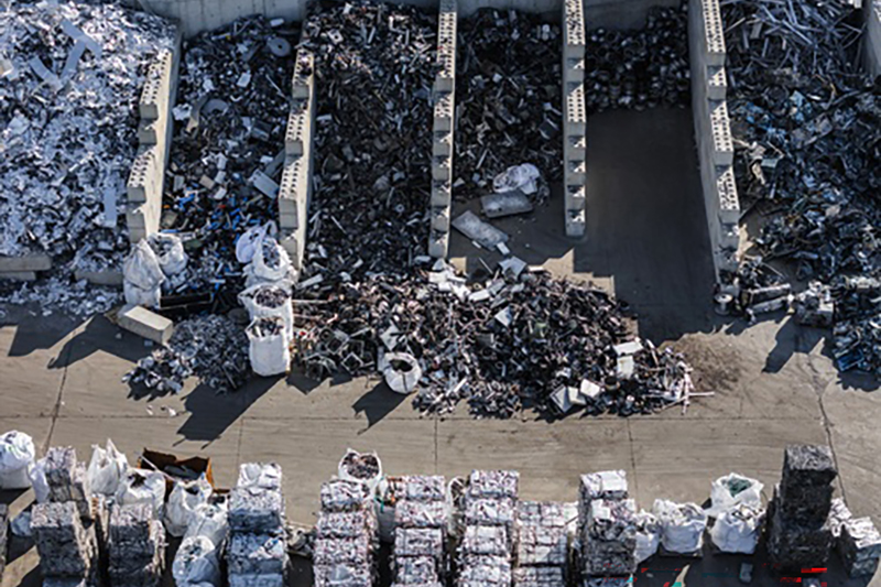 Part of a recycling facility from above - with different materials in divided areas with crushed squares of recycled material in compressed packages