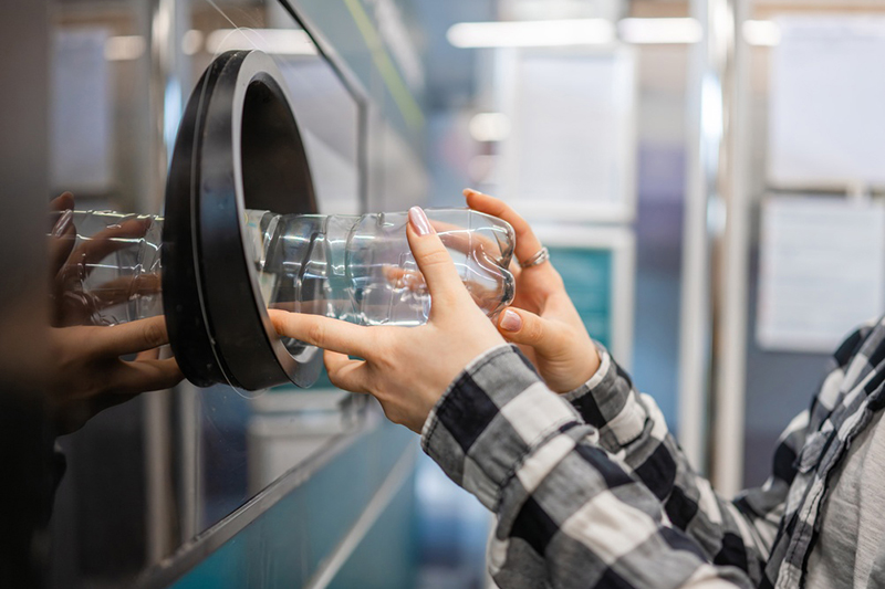 Girl Returning Empty Plastic Bottles In A Machine In The Supermarket, Showing A Close-Up Of Hands