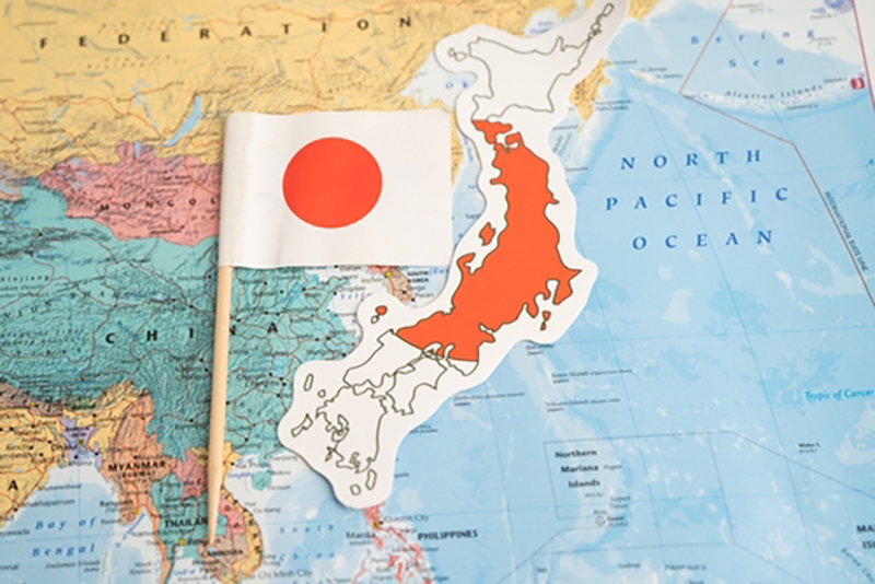 A cut out of Japan on top of a world map with a japanese flag