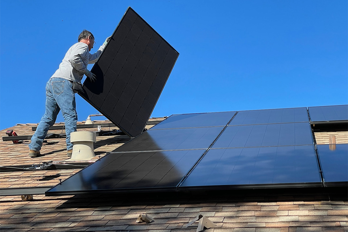 Worker adding solar panels to a roof