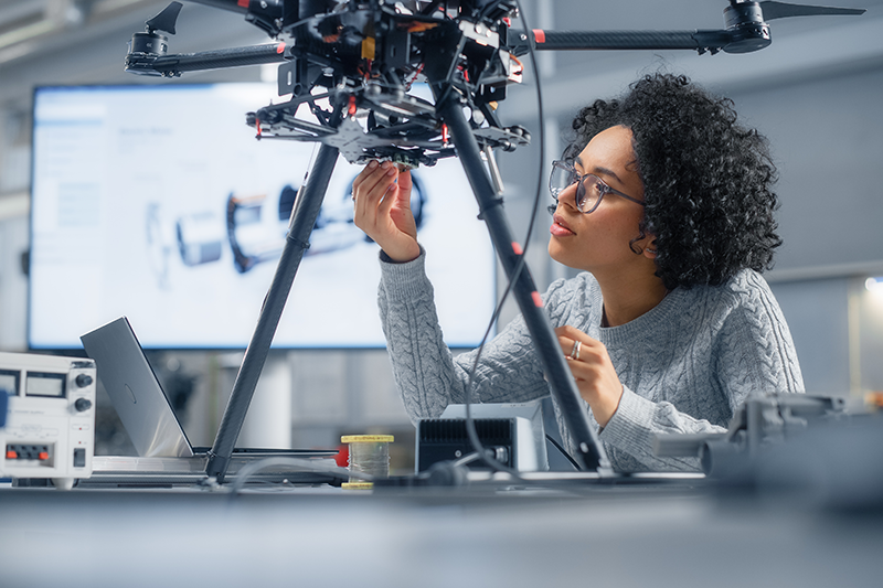Stock image of a woman fixing a part to a drone