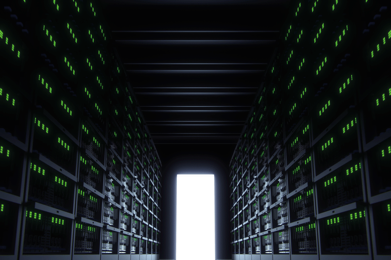 A dark corridor with computers on the side and an open door