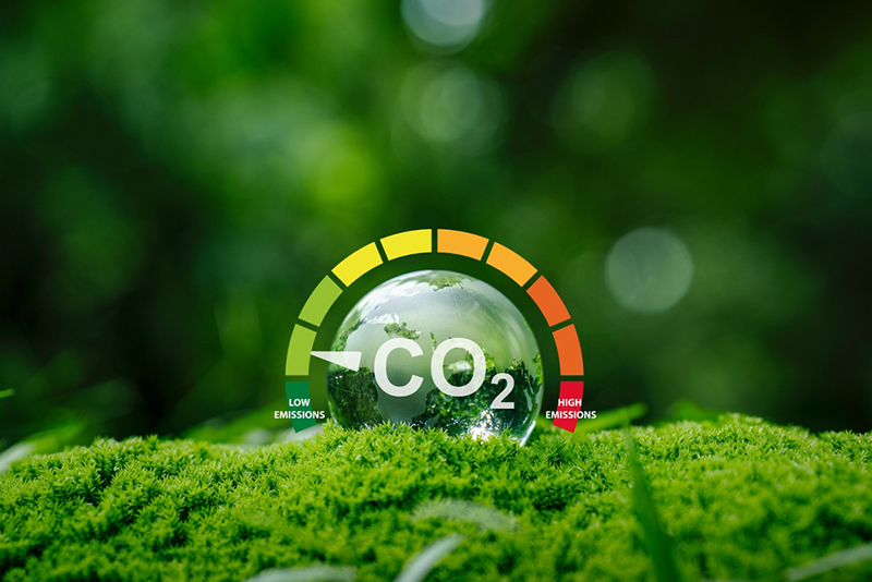Dial for low emissions and high emissions of CO2 set against a green foliage background