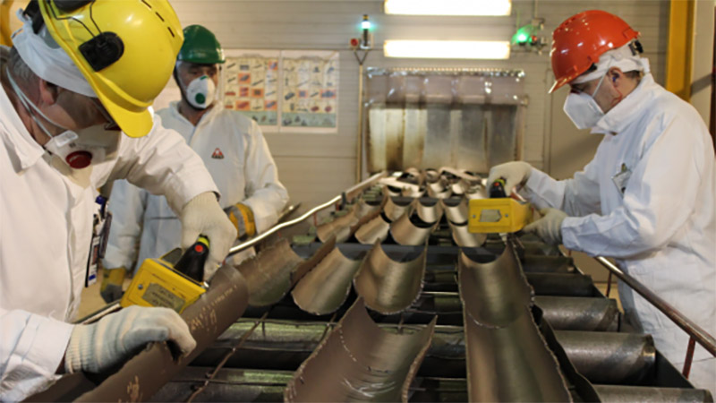 Workers dismantling the turbine hall at Ignalina Nuclear Power Plant measure scrap metal for traces of radiation