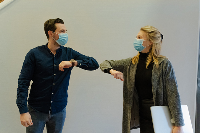 two people in masks bumping elbows by way of greeting