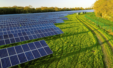 arrays of solar panels in a field in evening sunshine