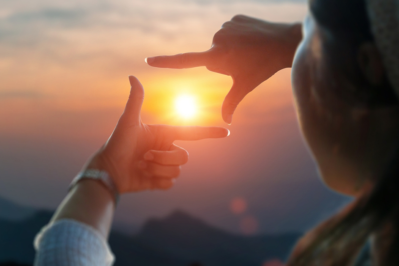 Close up of female hands making frame gesture view distant over sunset. Future planning idea concept.