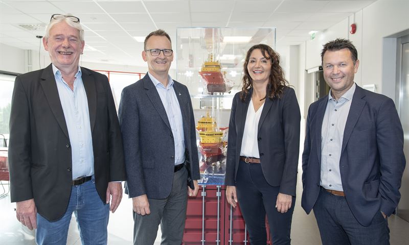 four smiling people in front of laboratory equipment