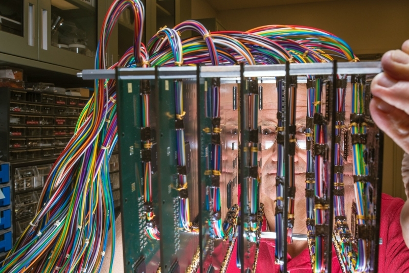 Scientist peers through an experimental setup of printed wiring