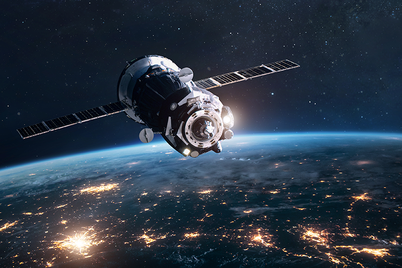 Stock image of satellite over Earth with lights showing cities on the surface