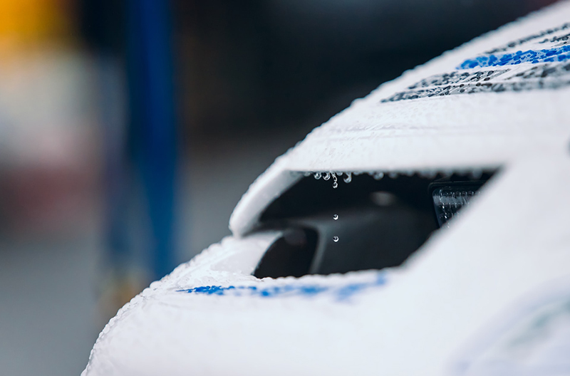 Car detail of a white and blue car with raindrops