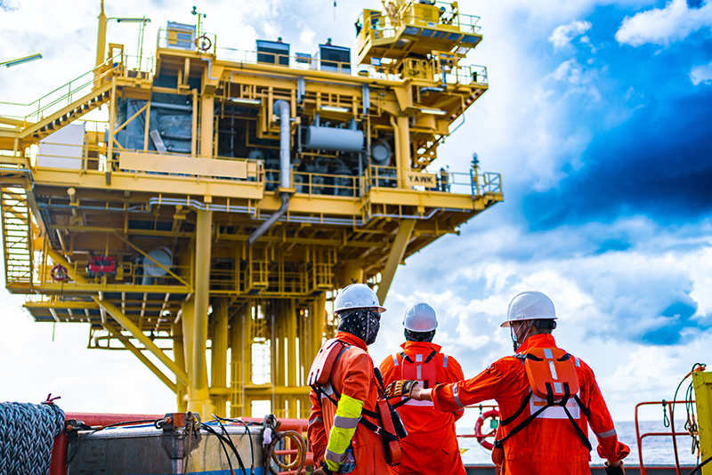 Oil rig workers looking up at an oil platform