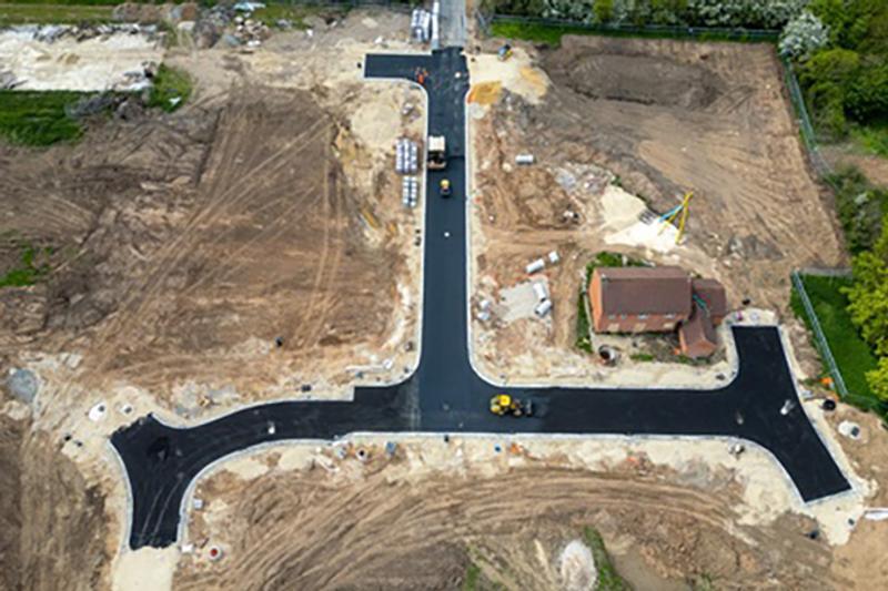 Aerial view of a construction site with newly paved roads, dirt areas, and a partially built house at Bellway Homes in Boroughbridge, UK