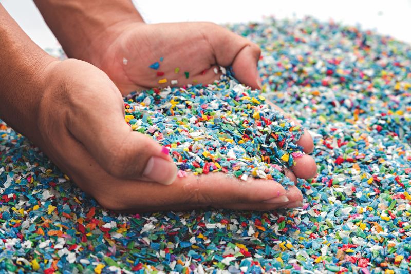 Small pieces of multi-coloured plastic cupped in two hands at the top of a pile pictured