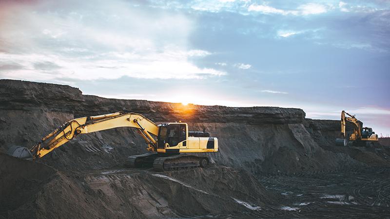 two yellow diggers against a dark earth background