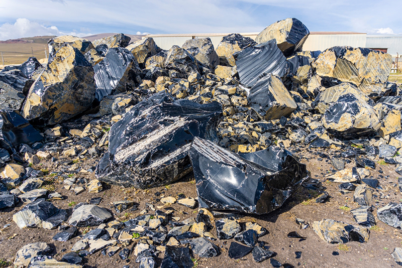 Volcanic glass (obsidians) on the ground under the rays of the sun