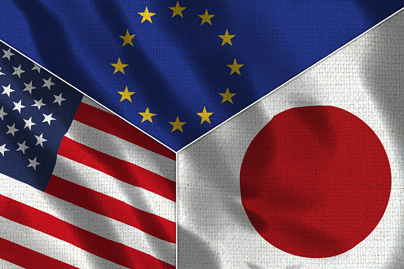 Flags of the EU (top third), US (bottom-left third) and Japan (bottom-right third)