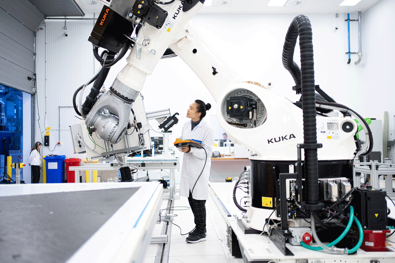 A woman looking at a robot in a white room