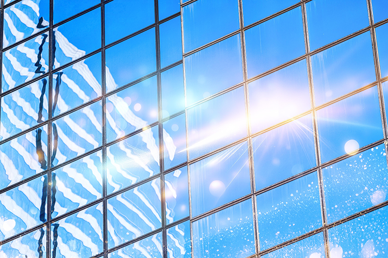 Stock image of a building reflected in another building's windows, with blue skies