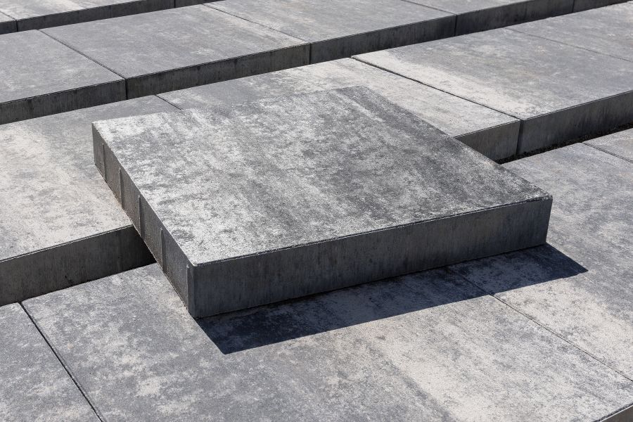 A large concrete paving slab of a square shape of grey light with stains pictured.