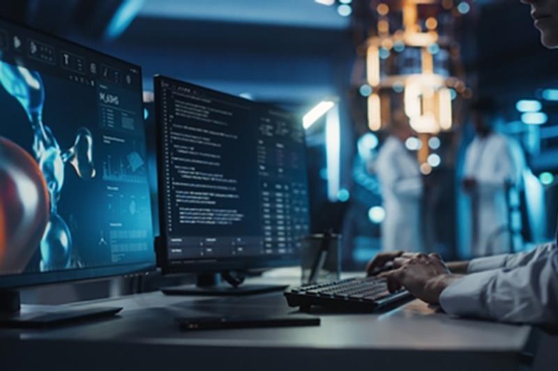 Researcher in a white coat at a computer station