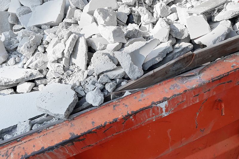 Construction rubble inside a red industrial waste container. Demolition debris and broken concrete pieces after renovation work