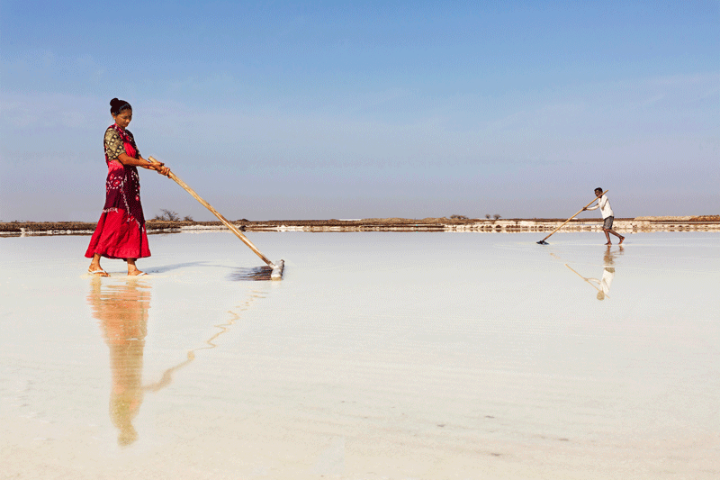 A woman and a man sweeping some liquid