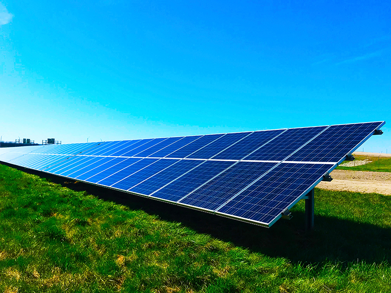 single row of solar panels in a green field