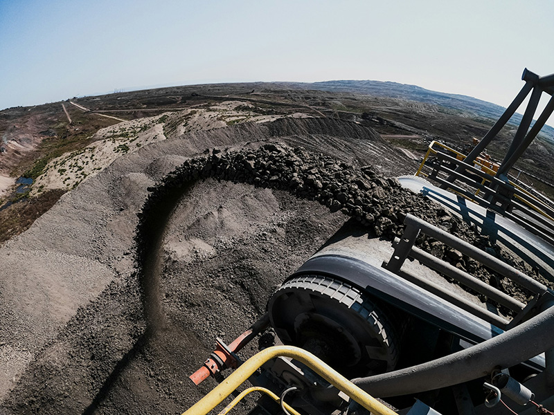 a pile of coal with an extractor to the right