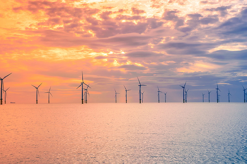 Sunset offshore wind turbine in a wind farm under construction off the England coast, UK