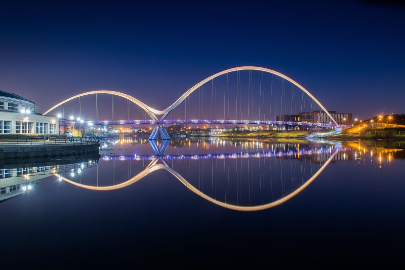 Infinity bridge Stockton On Tees with mirror reflection taken at night, the bridge forms two arcs across the water