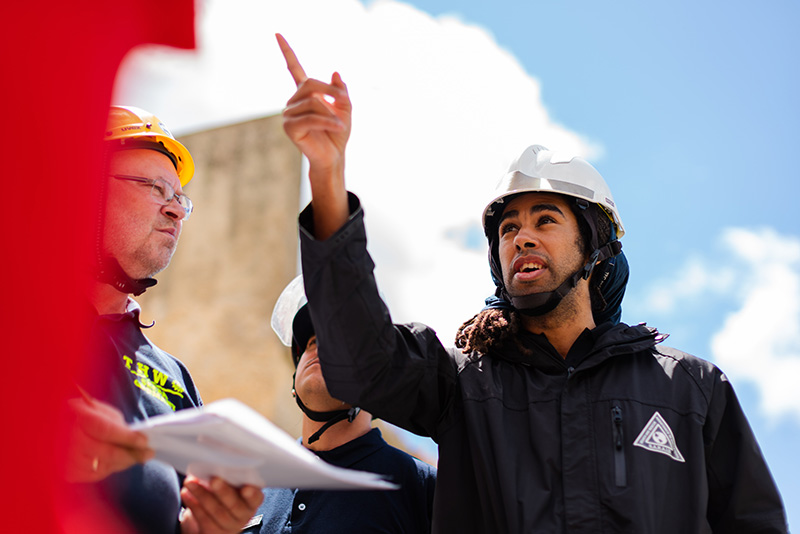 Building site with young man talking to older builder