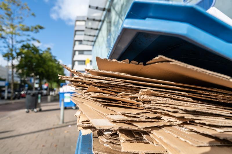 Flattened cardboard for recycling in a bin outside blocks of flats