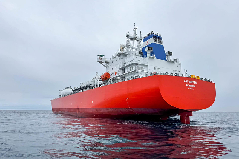 A large ship at sea going away, with the name ANTWERPEN visible - with a lot of pipework and container visible, with a high cockpit tower