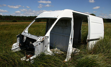White metal parts of a van sitting in a field of long grass