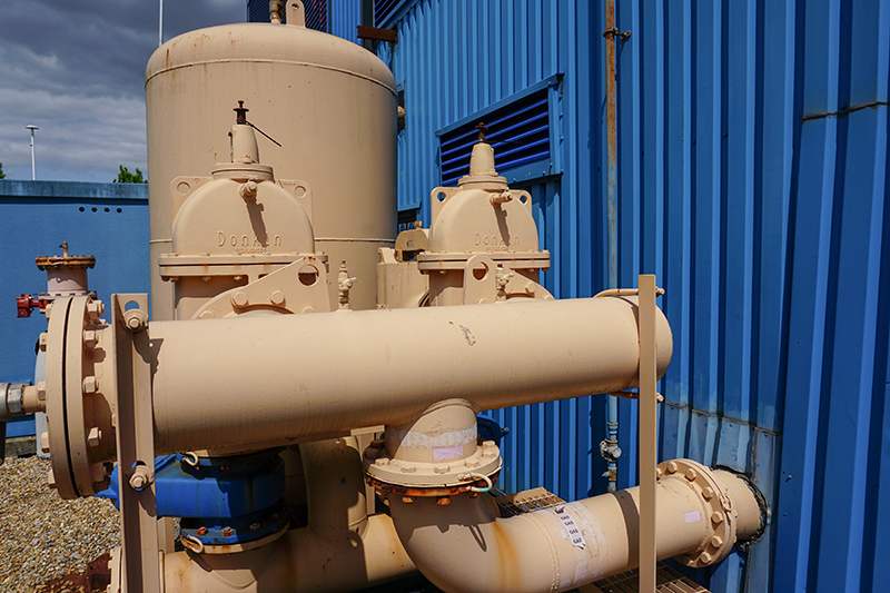 Stock image of beige geothermal pipes against blue walls outside a Southampton geothermal plant
