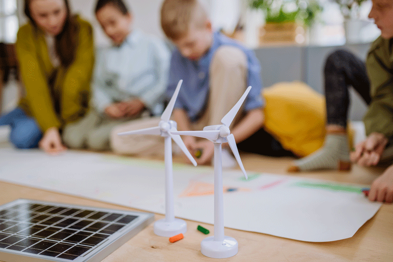 Children in a classroom with a miniature wind turbine in the foreground