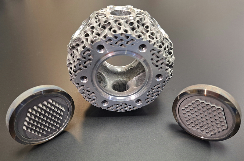 Three examples of 3D-printed, textured, shiny metal vacuum fittings coated with particle-absorbing material