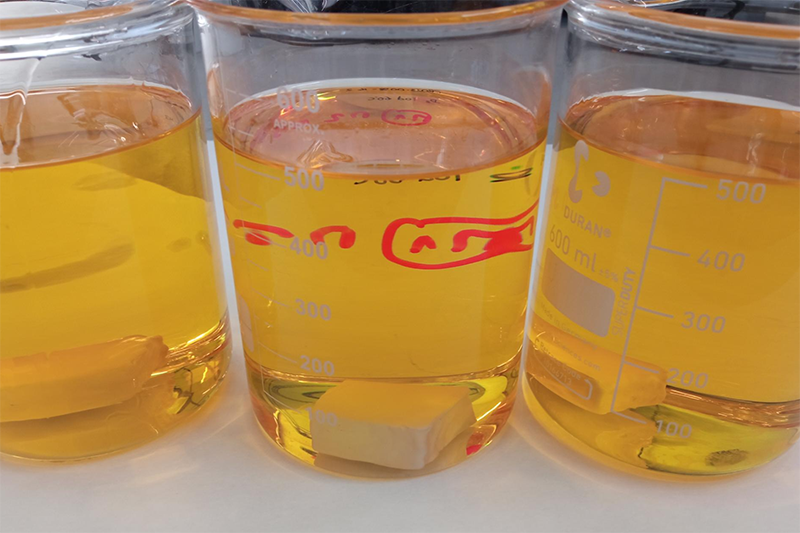 Beakers with orange-coloured solutions for safer BPA coatings