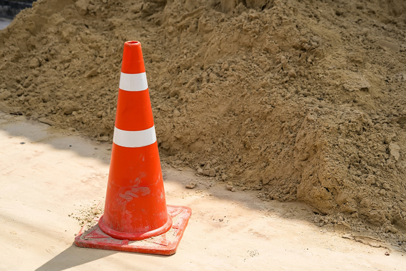 Bright orange traffic cone placed on a sandy construction sit