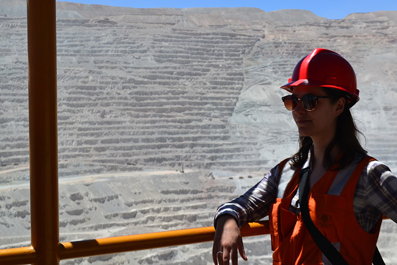 woman in a hard hit with an open cast mine in the background